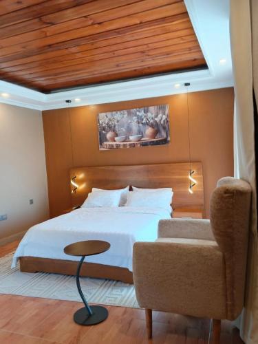 a bedroom with a white bed and a chair at Capri Hills in Mwanza