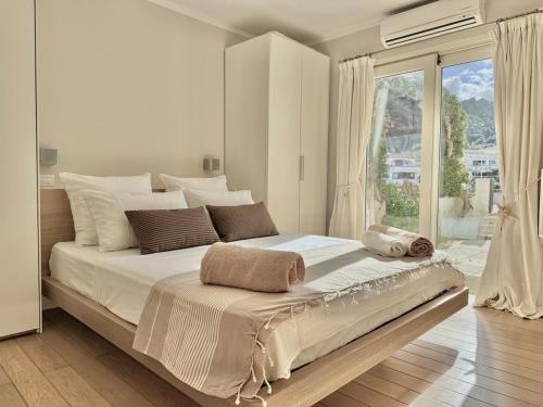 a white bedroom with a large bed and a large window at Poltu Quatu House in Porto Cervo