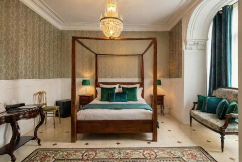 a bedroom with a canopy bed and a couch at Logis Hôtel & Restaurant Chateau de la Marjolaine in Essômes-sur-Marne