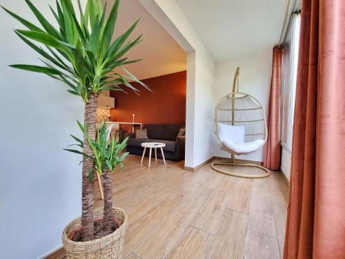 a living room with two palm trees and a chair at Écrin de Verdure - Design & Confort T2 38m2, WIFI, Piscine & Plage à 200m in La Grande Motte