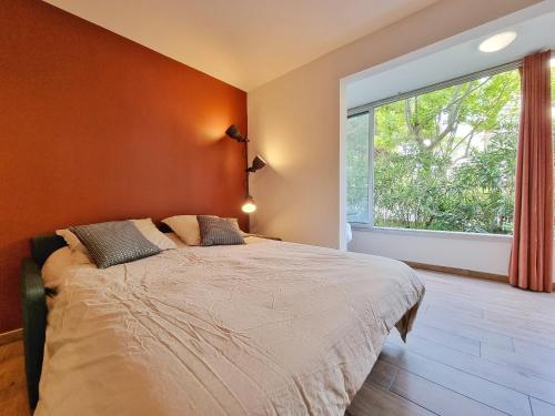 a bedroom with a bed and a large window at Écrin de Verdure - Design & Confort T2 38m2, WIFI, Piscine & Plage à 200m in La Grande Motte