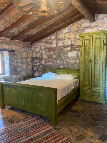 a bedroom with a green bed in a stone wall at Pavelin yeri in Altınoluk