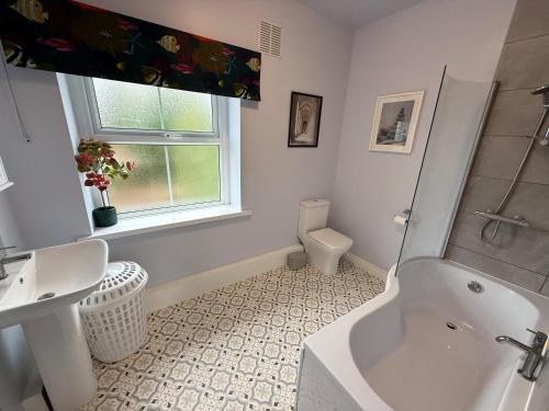 a bathroom with a tub and a sink and a toilet at New! Luxury 4 Bedroom Detached House - Central Baslow in Baslow