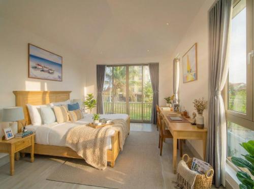 a bedroom with a bed and a desk and a window at Entire Hoi An Villas By Ovui in Hoi An