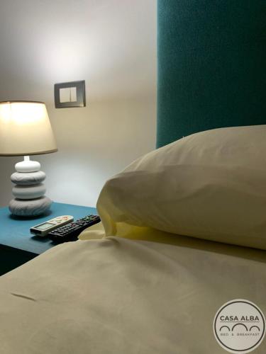 a bed with a pillow and a lamp on a table at Casa Alba in Taranto