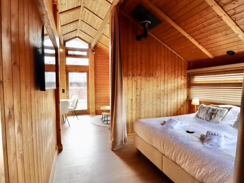 a bedroom with a large bed in a wooden room at Chalet Olive in Durbuy