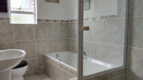 a bathroom with a tub and a toilet and a sink at Anchorage in Stompneusbaai