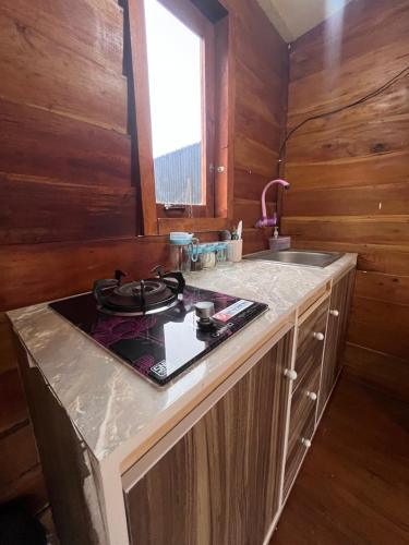 a kitchen with a stove and a sink at Cabin Hillside Dieng in Diyeng