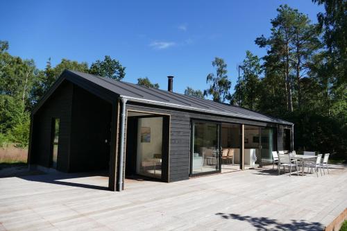 a black house with glass doors on a wooden deck at New luxury summerhouse near forest and beach in Frederiksværk