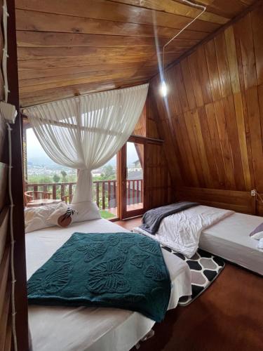 two beds in a room with a window at Cabin Hillside Dieng in Diyeng
