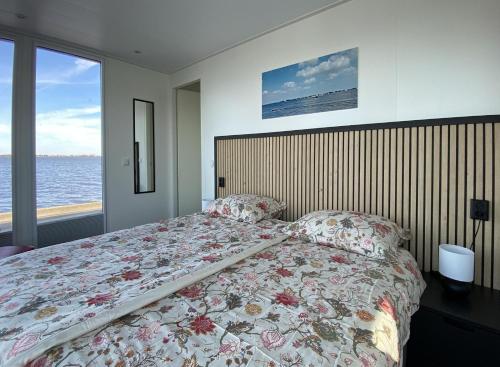 a bedroom with a bed with a floral bedspread at Houseboat Robbedoes in Offingawier