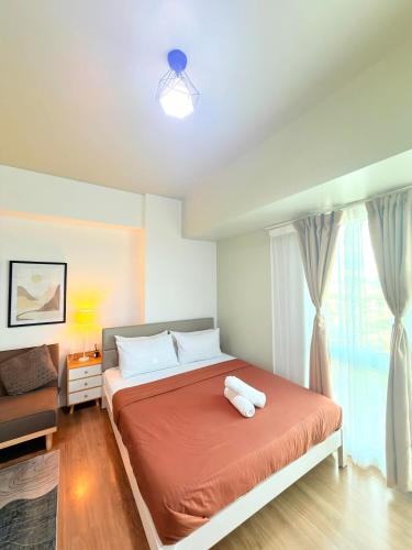 a bedroom with a bed with orange sheets and a window at Abreeza place T-2 in Davao City
