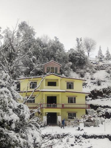 a yellow house is covered in snow at Mayadeep Resort and Hostels in Chopta
