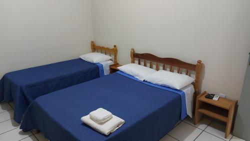 zwei Betten in einem Zimmer mit blauen Laken und weißen Kissen in der Unterkunft Pousada Parque in Mostardas