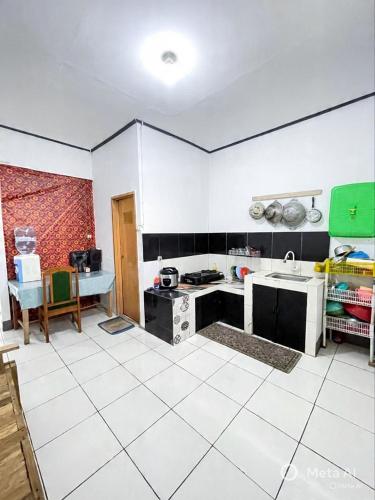 a kitchen with white and black walls and a white tile floor at Tiga Dara Homestay 3 in Pangandaran