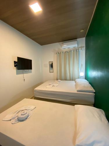 two beds in a small room with a tv at Pousada da Mangueira 1 in Barreirinhas