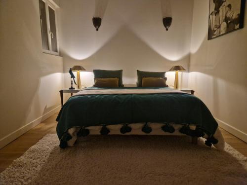 a bedroom with a bed with a green comforter at Gîte, jacuzzi et piscine in Cintegabelle