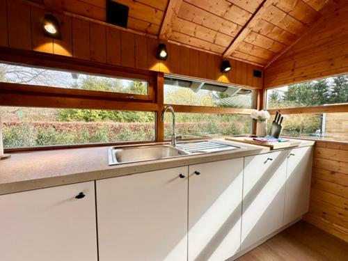 eine Küche mit Spüle und Fenster in der Unterkunft Chalet Marron in Durbuy