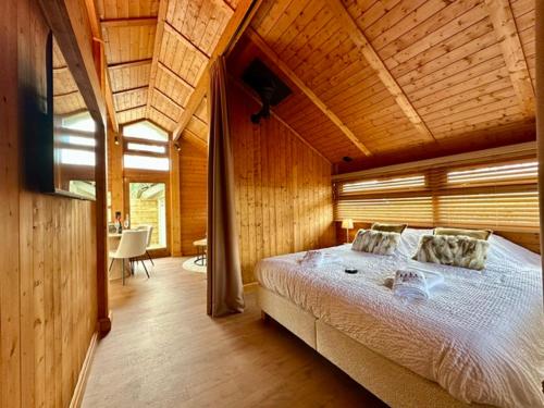 ein Schlafzimmer mit einem großen Bett und einer Holzdecke in der Unterkunft Chalet Marron in Durbuy
