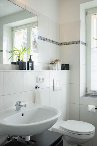 a white bathroom with a sink and a toilet at Central Station Apartment in Dessau