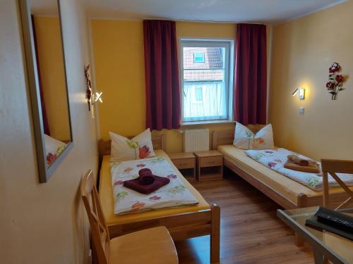 a small room with two beds and a table at Frühstückspension "Metilstein" in Eisenach