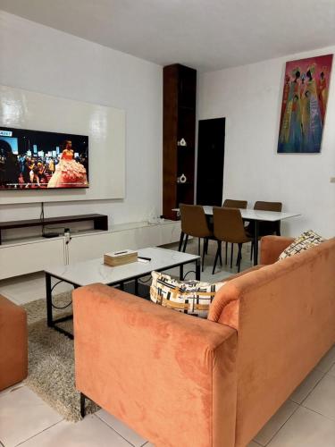 a living room with a couch and a flat screen tv at SEJOURABIDJAN - Residences Cocody Angré in Abidjan