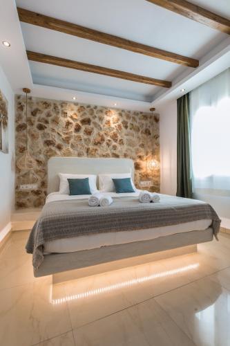 a bedroom with a large bed with a stone wall at Naxos Grand Hotel in Agios Prokopios