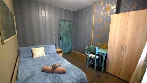 a bedroom with a bed with a blue blanket and a desk at Nayri HOUSE Самоков,село Доспей in Dospey