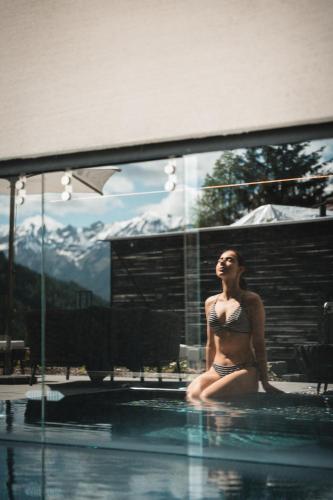 Eine Frau im Bikini sitzt in einem Schwimmbecken in der Unterkunft ARPURIA - 4 Star Superior - Adults Only in Sankt Anton am Arlberg