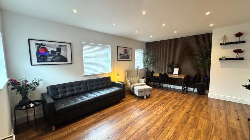 a living room with a black leather couch and a dining room at Modern 2 Bedroom Apartment near Crosby Beach & Liverpool in Crosby
