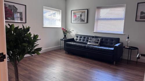 a living room with a black couch in a room at Modern 2 Bedroom Apartment near Crosby Beach & Liverpool in Crosby