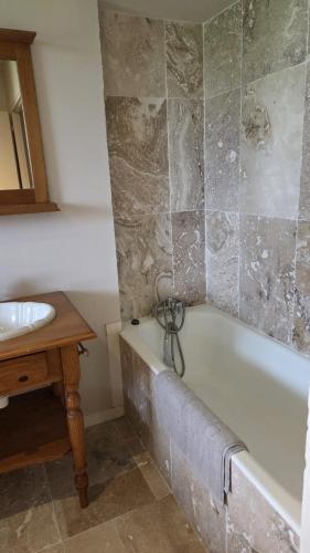 a bathroom with a bath tub and a sink at Petit Gîte à la campagne in Brains-sur-Gée