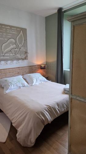 a bedroom with a large bed with white sheets at Petit Gîte à la campagne in Brains-sur-Gée