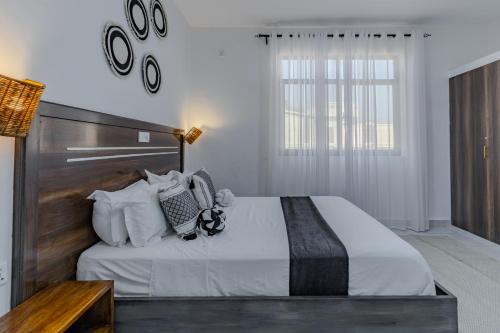 a bedroom with a large bed with a wooden headboard at Wendy's Da-Azizi Homes Diani 2 in Diani Beach