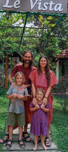 a family posing for a picture under an umbrella at Le Vista Resort in Sultan Bathery