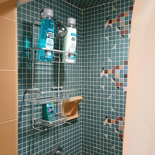 a green tiled shower with two bottles of cleaning products at Cliffside Cottage in Mansfield