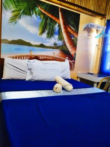 a bedroom with a blue bed with a painting on the wall at Hotel Tagudan Kubo Corporation in Tagudin