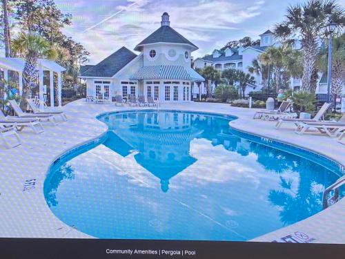 a swimming pool in front of a house at First Class Treatment Luxurious end unit Patio Pool Restaurant Bar on premises Steps away from Everything else! Spacious Condo Stocked with all You Need! in Myrtle Beach