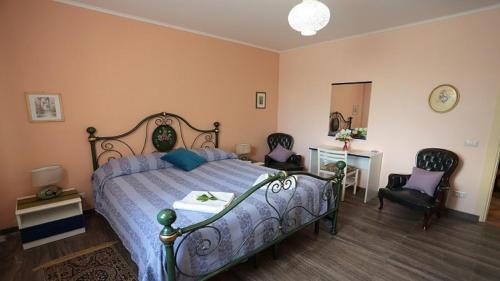 a bedroom with a bed and two chairs and a mirror at Holiday Maison Villa Arci in Giardini Naxos
