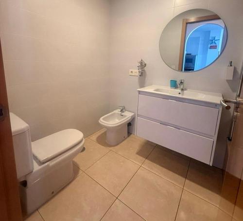 a bathroom with a toilet and a sink and a mirror at La Perla Beach Apt with Pool in El Médano