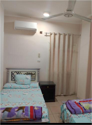 a bedroom with two beds and a window with a fan at الغردقة - اول ممشى شيرى in Hurghada