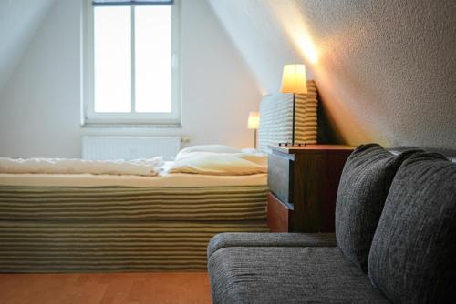 a bedroom with a bed and a couch and a window at Ostsee43 - Apartment Ole in Rostock
