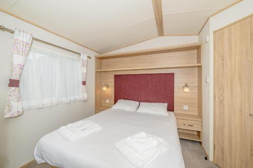 a bedroom with a large white bed and a window at Castle Brake Holiday Park in Woodbury