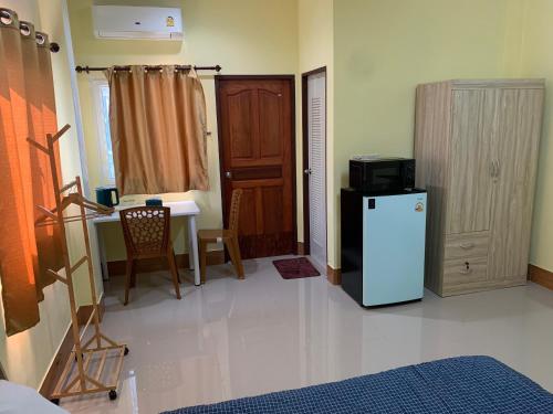 a room with a refrigerator and a table with a desk at ท่าเรือห้องพัก Tha Ruea hongpak in Ban Na Sat
