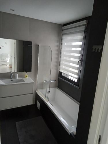 a bathroom with a tub and a sink and a window at Villa Lisbonne piscine plage in Aroeira