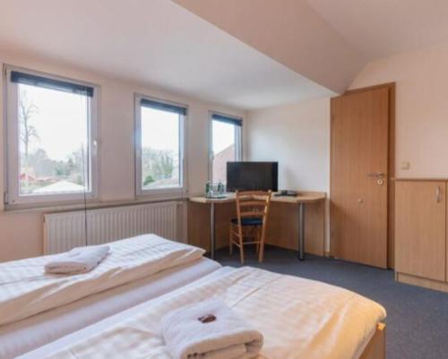 a bedroom with a bed and a desk with a computer at Altes Posthaus Ahlhorn in Großenkneten