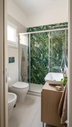 a bathroom with a toilet and a sink with a plant mural at Equi60 in Rome