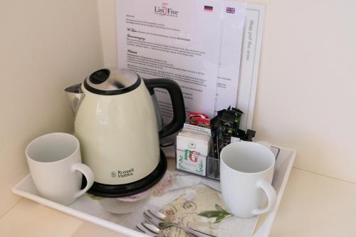 a coffee pot and two cups on a shelf at List Five - Your British Guesthouse in Stuttgart