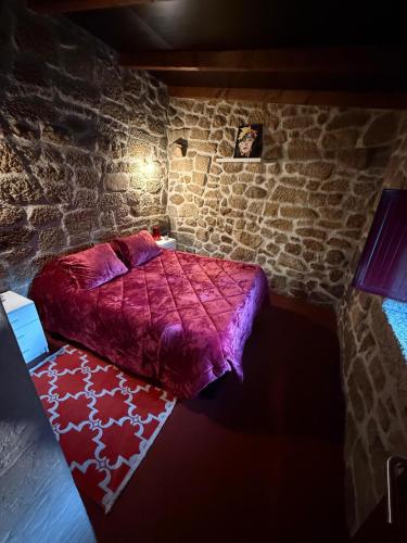a bedroom with a bed in a stone wall at Casa Portela in Marialva