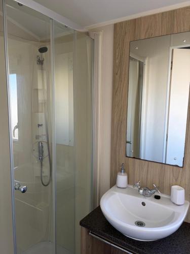 a bathroom with a white sink and a shower at PG173 Golden Palm Resort 6 Berth Caravan With Decking in Chapel Saint Leonards